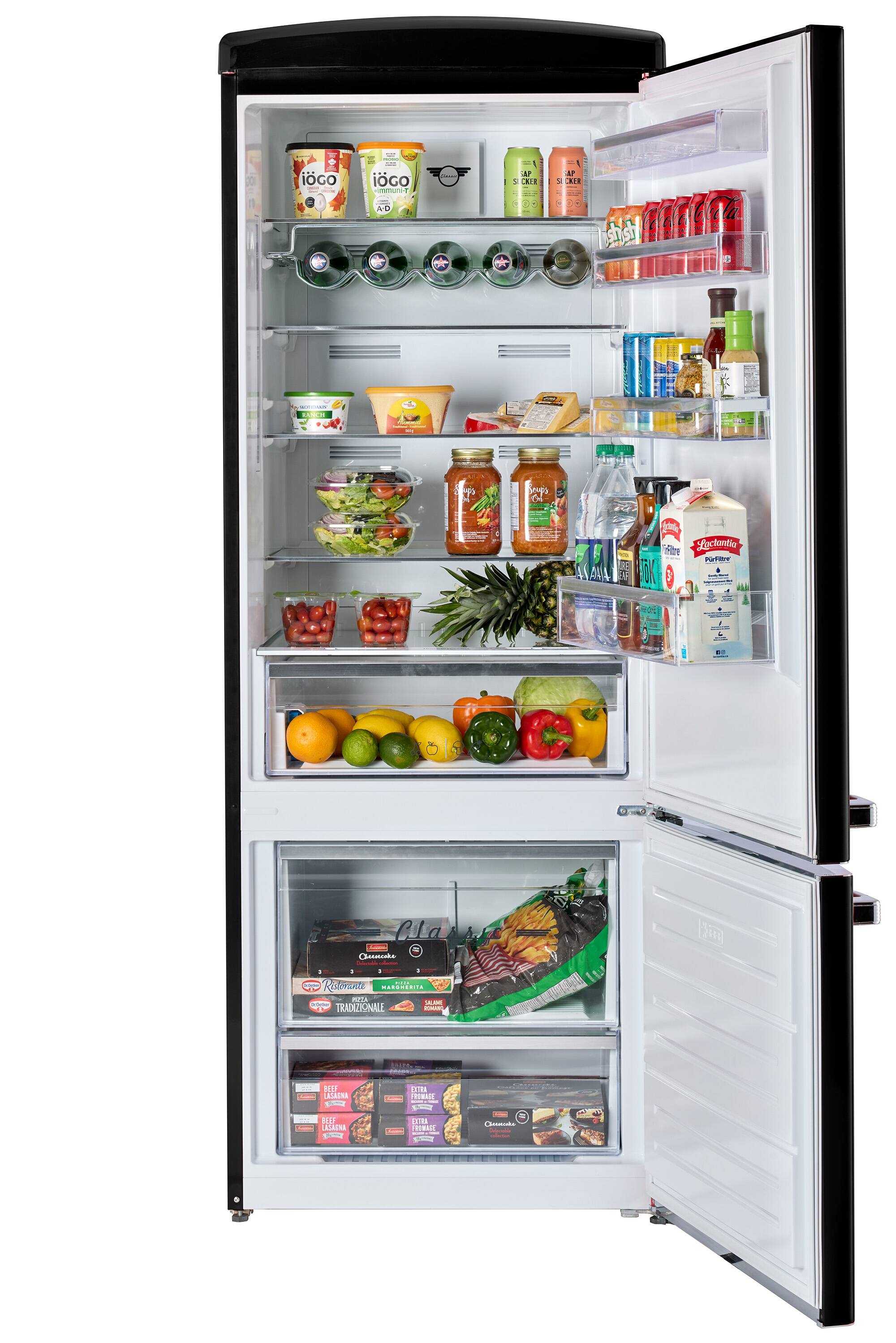 The image shows a refrigerator with its door open, revealing a variety of food items inside. There are multiple bottles, including a bottle of wine, and a few oranges placed in different compartments of the refrigerator. The refrigerator is stocked with a variety of food items, making it an ideal place for storing and preserving perishable goods.