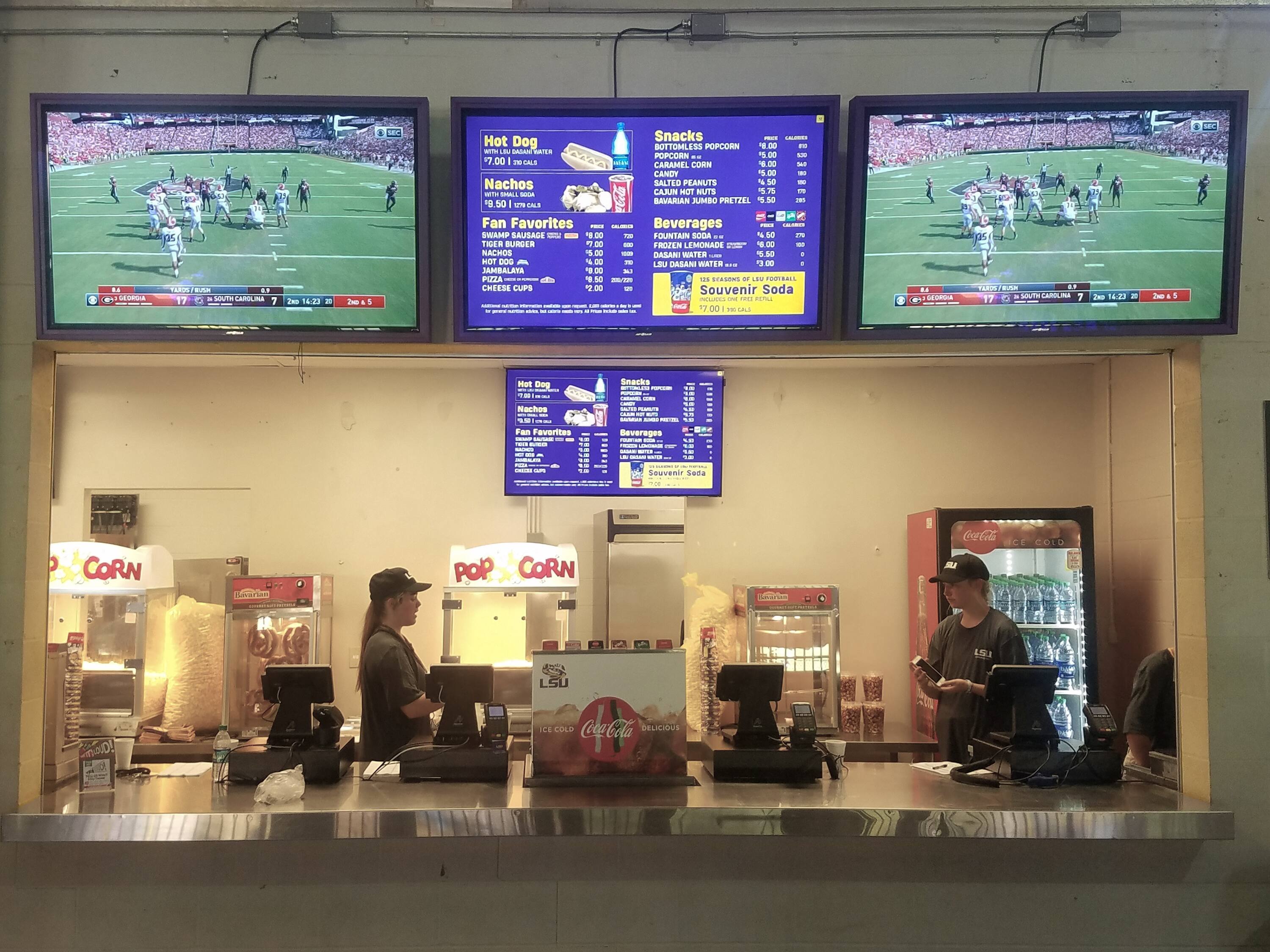 a. 4 SA TARIN BUS . 1 SIUTE LABILAN 7 2u 1673 - - 1 Hot Dog - Bottomless Popcorn - - - Caramel Corn 1.00 - Nachos - Salted Peanuts 4.50 - Cajun Nuts 7.00 - Bavarian Jumbo Pretzel 5.00 - Fan Favorites - Swamp Sausage - Tiger Burger - Jambalaya - Cheese Cups 7.00 - Beverages - Fountain Soda - Frozen Lemonade 1.50 - Dasani Water 1.50 - Souvenir Soda 1.00 - Souvenir Cheese Cups 7.00 - Hot Dog - Nachos - Fan Favorites - Souvenir Soda - Popcorn - Coca-Cola