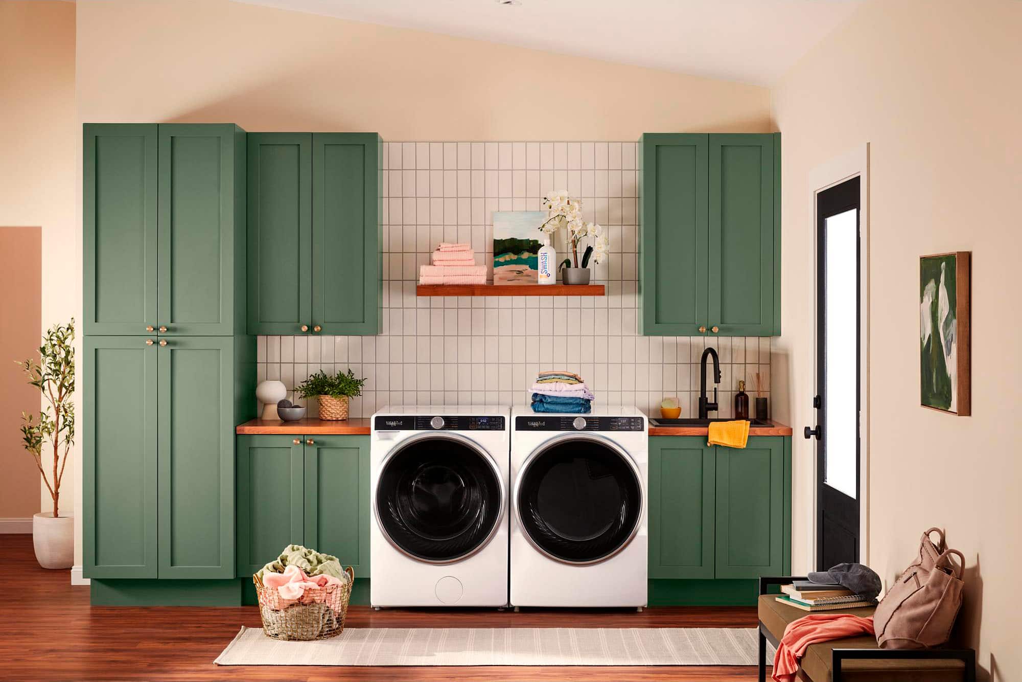 The text "SWASH Sggr" is not present in the image. The image shows a kitchen with green cabinets, a washer and dryer, and a potted plant.