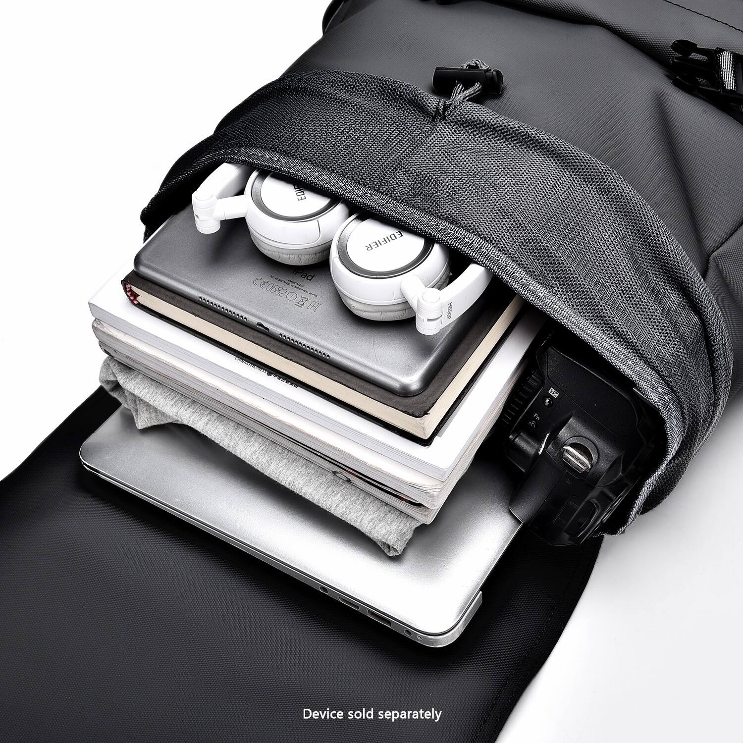 The image shows a backpack with a variety of electronic devices and books inside. The backpack is filled with a laptop, a tablet, a cell phone, and a pair of headphones. The headphones are placed on top of the laptop, and the cell phone is located in the middle of the backpack. The books are placed on top of the electronic devices, with one book on top of the laptop and another book on top of the tablet. The backpack is packed full, indicating that it is being used to transport these items.