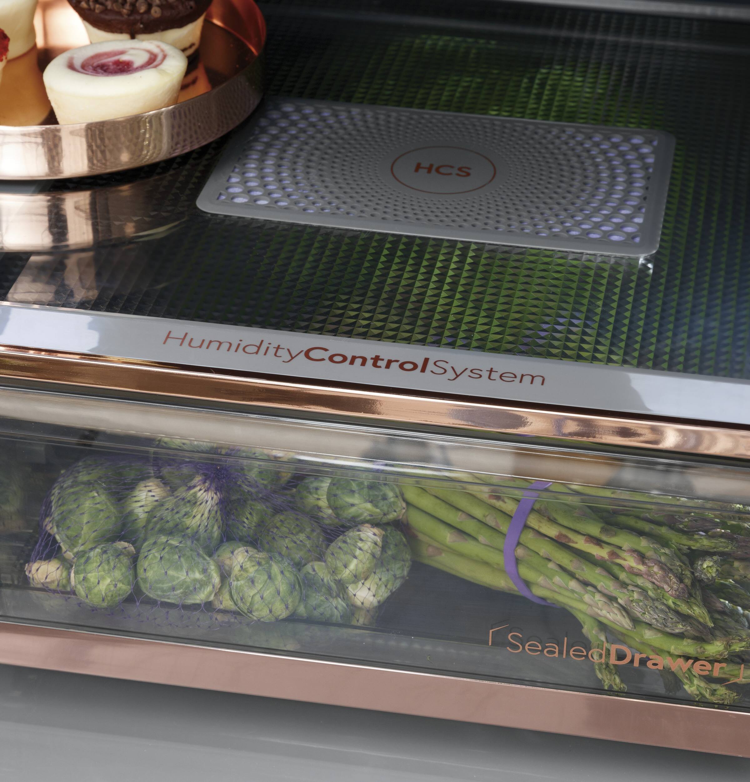 The image features a humidity control system with a drawer full of vegetables, including asparagus and broccoli. The vegetables are placed in a clear container, and there is a scale on top of the drawer. The humidity control system is designed to maintain a consistent humidity level for the vegetables, ensuring their freshness and quality. The presence of a scale on top of the drawer suggests that the system may also be used for monitoring the weight of the vegetables, which can be helpful for inventory management and tracking their freshness.