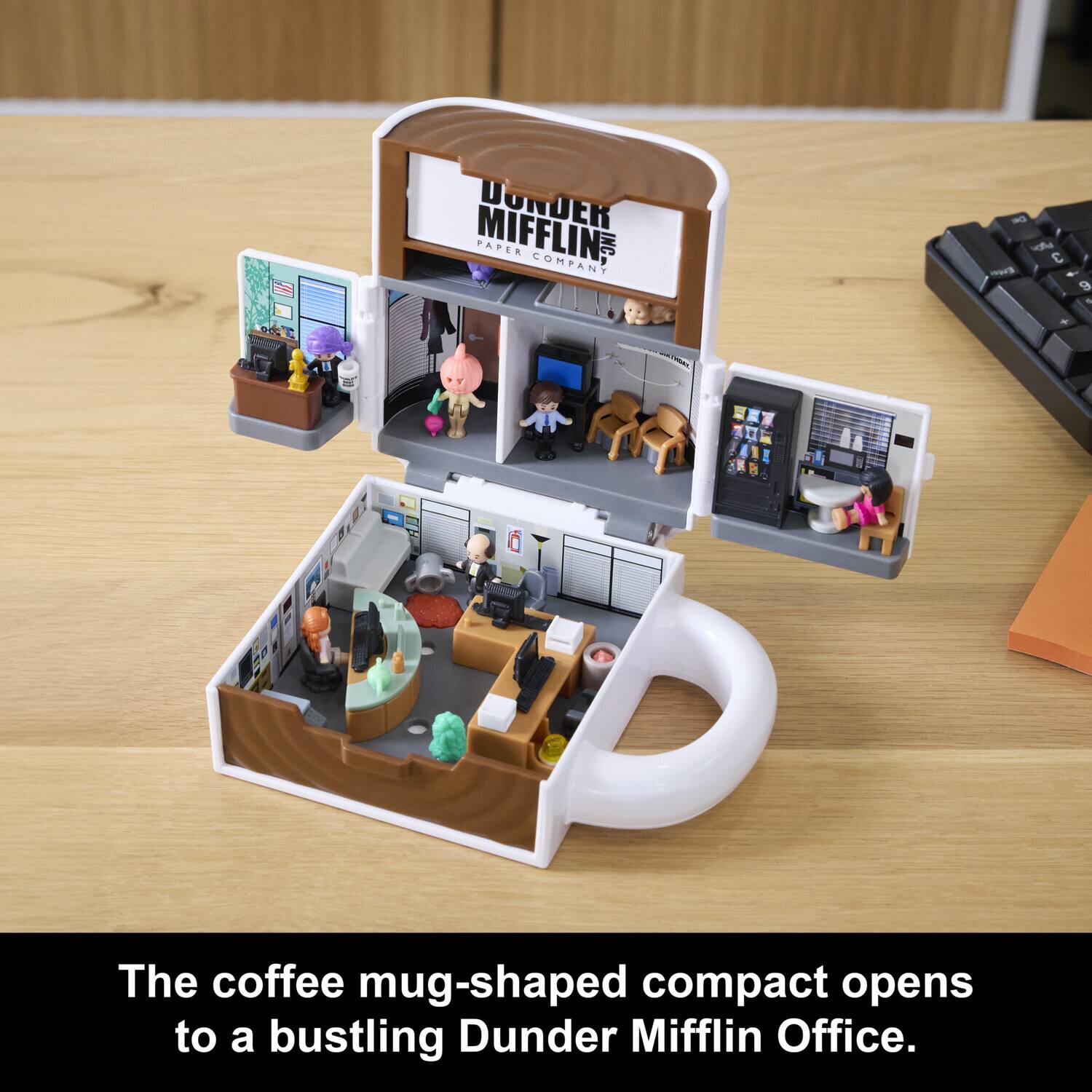 The coffee mug-shaped compact opens to a bustling Dunder Mifflin Office. DONDER DER MIFFLINS PAPER COMPANY l C 1 9 .