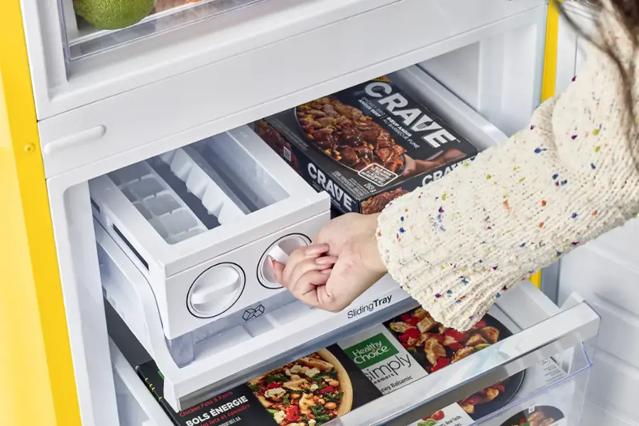 A person is opening a refrigerator and pulling out a Crave beef barbecue package. The refrigerator also contains a variety of other food items, such as apples, oranges, and broccoli.