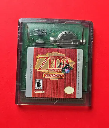The text on the image is: "GAME BOY THE LEGEND OF ZELDA ORACLE OF SEASONS CGB-AZ7E-USA EVERYONE Nintendo" - E (Everyone)