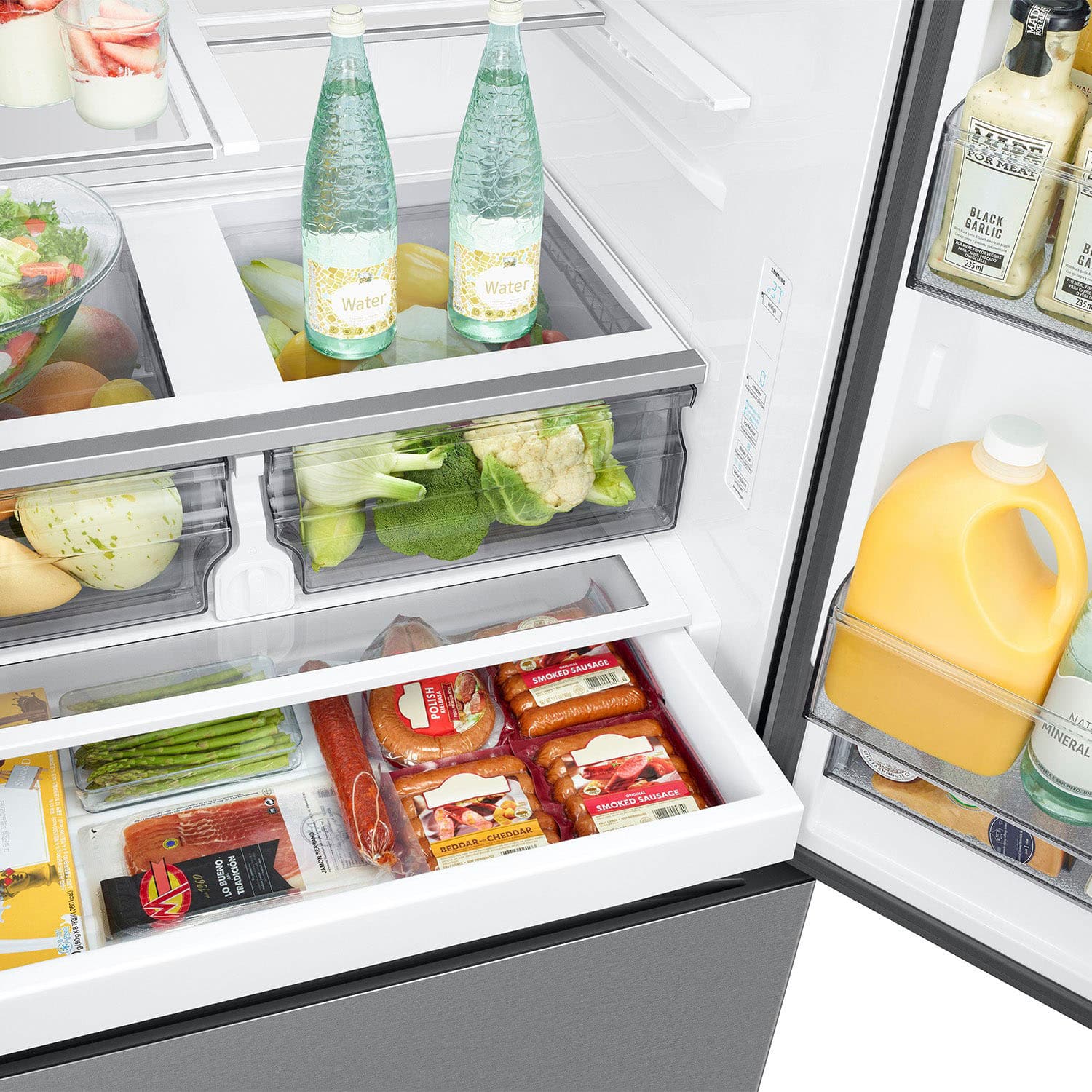 The refrigerator is filled with a variety of food items and drinks. There are two bottles of water, one on the top shelf and the other on the middle shelf. Additionally, there are two bottles of juice, one on the top shelf and the other on the bottom shelf. The refrigerator also contains a bowl of fruit, which is placed on the top shelf. The refrigerator is well-stocked with a diverse range of items, including meat, vegetables, and beverages.