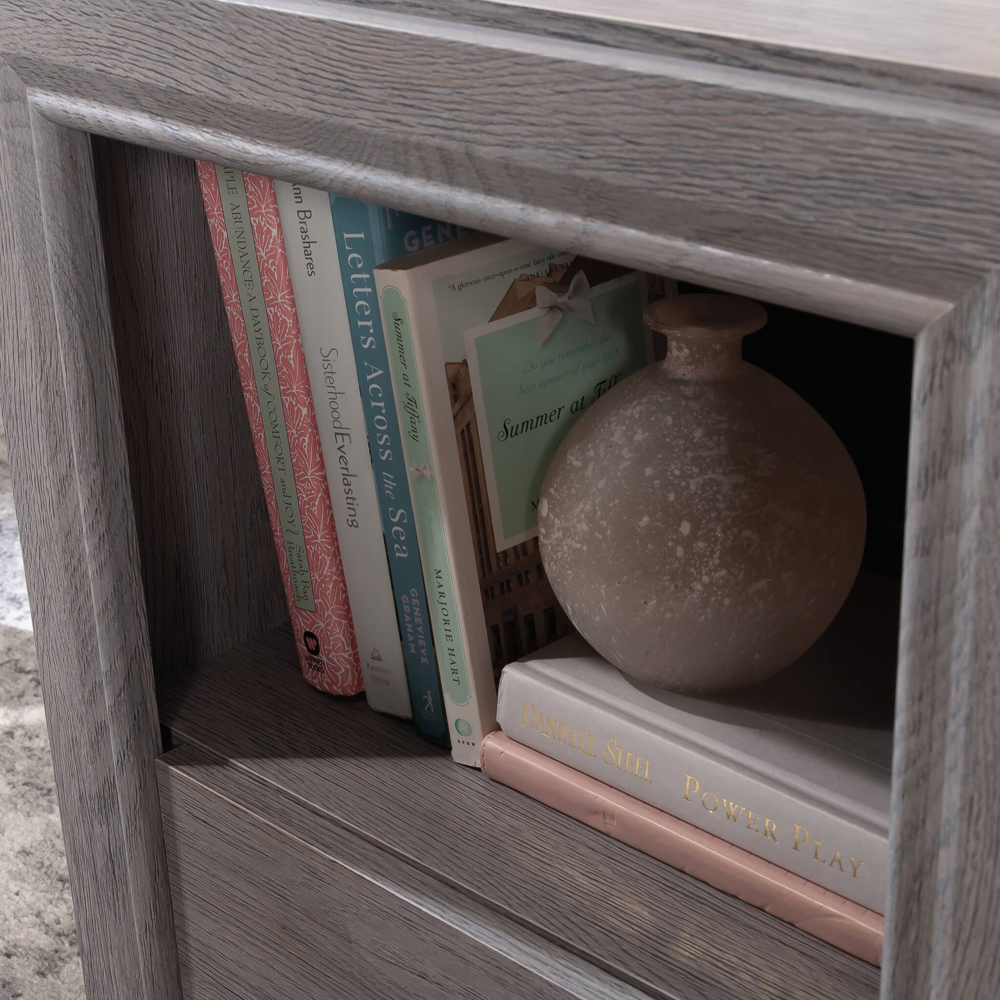 Sure, here is the corrected and grouped text from the image:

1. **Books:**
   - "Home Again" by Danielle Steel
   - "Sisterhood Everlasting" by Danielle Steel
   - "Letters Across the Sea" by Genevieve Graham
   - "Summer at the Ritz" by Genevieve Graham
   - "Power Play" by Danielle Steel

2. **Decorative Item:**
   - "Summer at the Ritz" (partially visible on the decorative item)

3. **Other Text:**
   - "Summer at the Ritz" (on the decorative item)