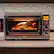 The image shows a Breville toaster oven with a turkey inside, cooking at 328 degrees. The oven is placed on a countertop, and it is filled with various food items, including a casserole dish. The oven is open, revealing the delicious meal being prepared.