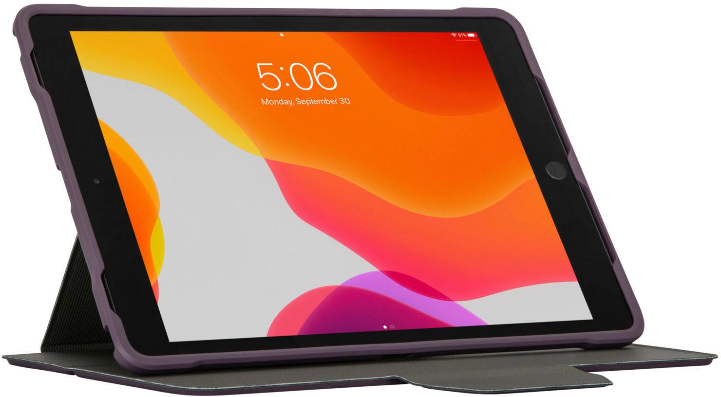 The image shows a purple tablet with a screen displaying the time of 5:06. It is sitting on a purple stand, which is placed on a purple table. The tablet is turned on and ready for use.