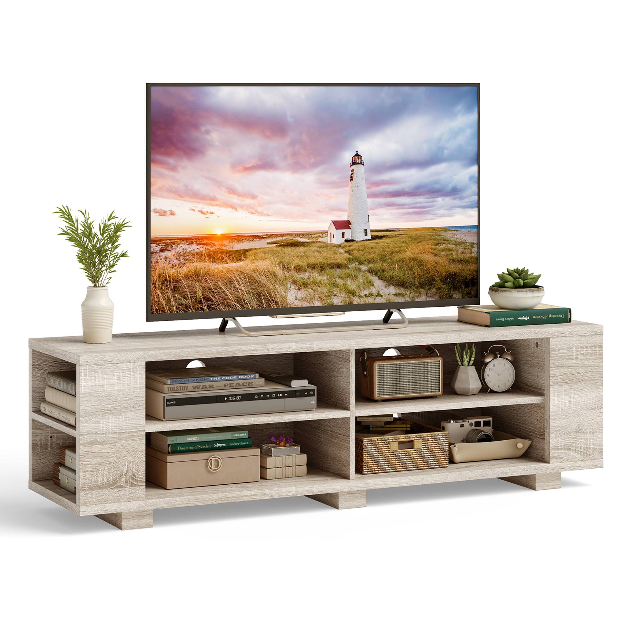 The image features a large flat screen TV placed on a wooden entertainment center. The TV is displaying a beautiful sunset scene with a lighthouse in the background. The entertainment center also has a variety of books and a potted plant, adding to the cozy atmosphere of the space.