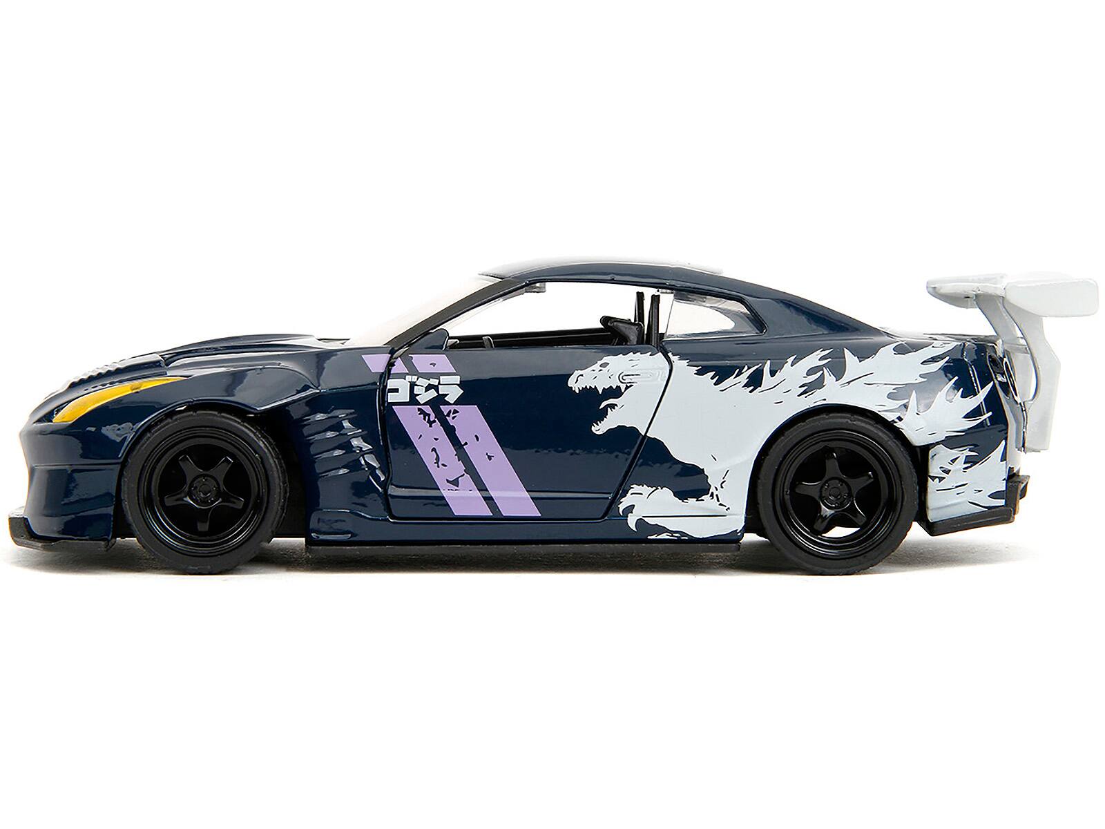 Left. Jada - 2009 Nissan GT-R (R35) Ben Sopra Dark Blue with Graphics "Godzilla" "Hollywood Rides" Series 1/32 - Dark Blue .