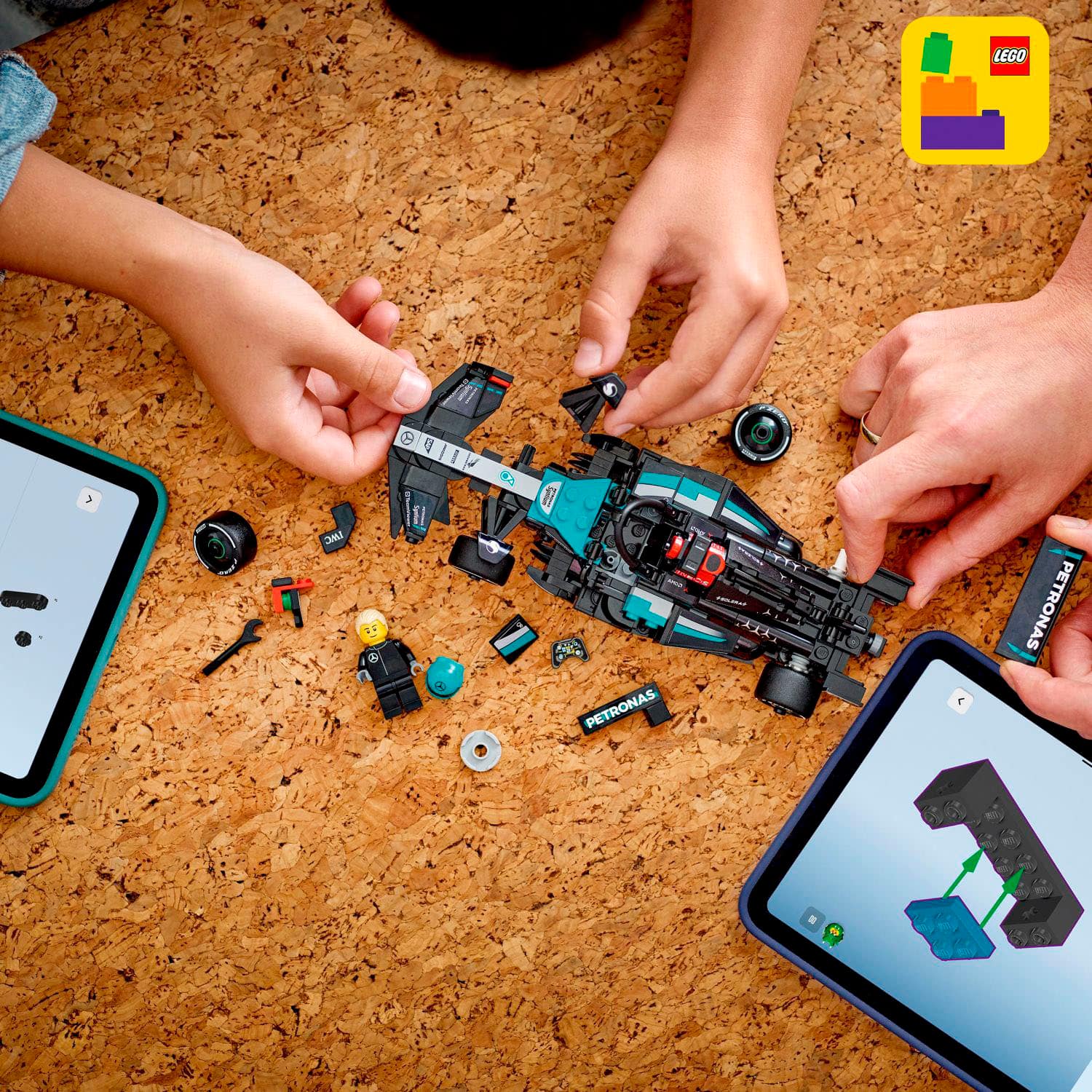The image shows a group of people working on a LEGO car, with a table full of LEGO pieces and instructions. They are using a tablet to help them assemble the car, and there are also two cell phones present in the scene. The people are focused on their task, and the table is covered with various LEGO parts, making it a fun and engaging activity for them.