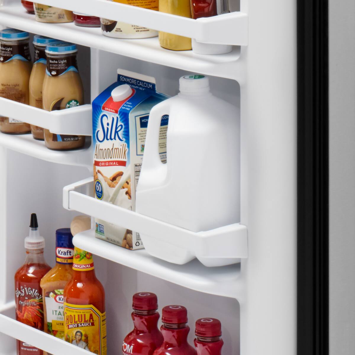 Sure, here is the corrected and grouped text from the image:

**Top Shelf:**
- ES D I
- da Light
- GE Nucha Light
- AUM - LEL Mecha Light

**Middle Shelf:**
- 50% MORE CALCIUM
- mr 2 85
- S O - U
- SA MON Silk
- Amondmilk ORIGINAL
- Nutr - OON 1
- 60

**Bottom Shelf:**
- Kraft LITE ORIGINAL
- ky Valley Kr
- zE - Ao - ITAL DRE HOLULA LITE SAUCE HOT
- O - -o - - OM