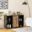 The image shows a small wooden cabinet with a shelf on top of it. The shelf holds a variety of items, including several bottles, a cup, a bowl, and a vase. The cabinet is placed on a carpeted floor, and there is a potted plant nearby. Additionally, there is a sewing machine on the cabinet, which adds a unique touch to the overall decor.