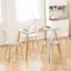 The image shows a modern glass dining table with four chairs around it. The table is set with plates, silverware, and a vase. There are also a few apples and a bowl on the table. The chairs are positioned around the table, creating a comfortable and inviting dining area.