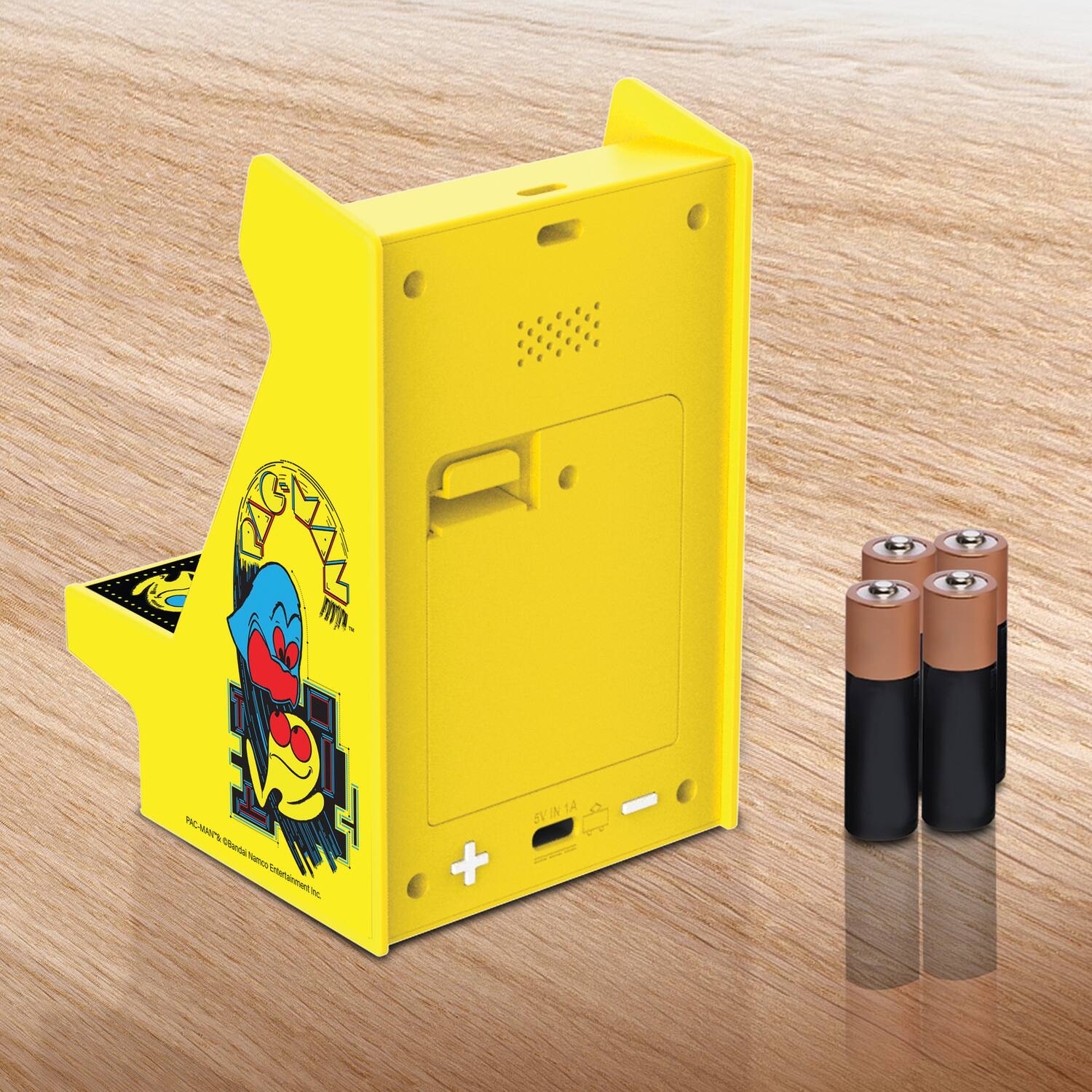 Sure, here is the corrected and grouped text from the image:

---

**Front Side:**

- "PAC-MAN'S ©BANDAI NAMCO entertainment inc."

**Top Side:**

- "IN 14"

**Battery Compartment:**

- "+" and "-" symbols

**Additional Text:**

- "TE aa Tu Amerammeet a - + SVINTA W TA S"

---

This text appears to be part of the design and branding on the device.