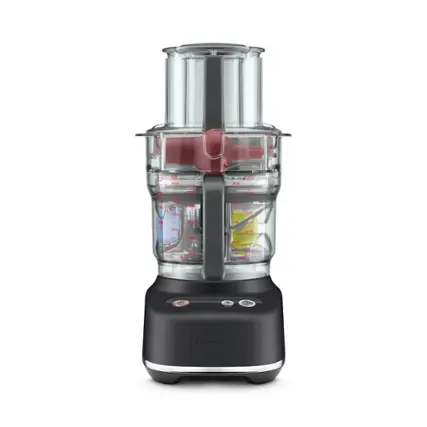 The image features a black and silver blender made by Breville. The blender is filled with various ingredients, including a cup and a spoon. The blender is designed to blend and mix ingredients together, making it a versatile appliance for preparing a variety of dishes and beverages.