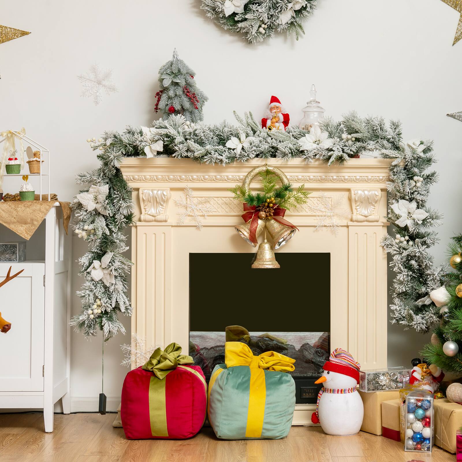 The image features a fireplace decorated for Christmas with a white mantle and a white Christmas tree. The fireplace is adorned with a variety of Christmas decorations, including a Santa Claus figurine and a snowman. The fireplace is also surrounded by presents, adding to the festive atmosphere. The scene is set in a room with a white wall, and there is a clock on the wall as well.