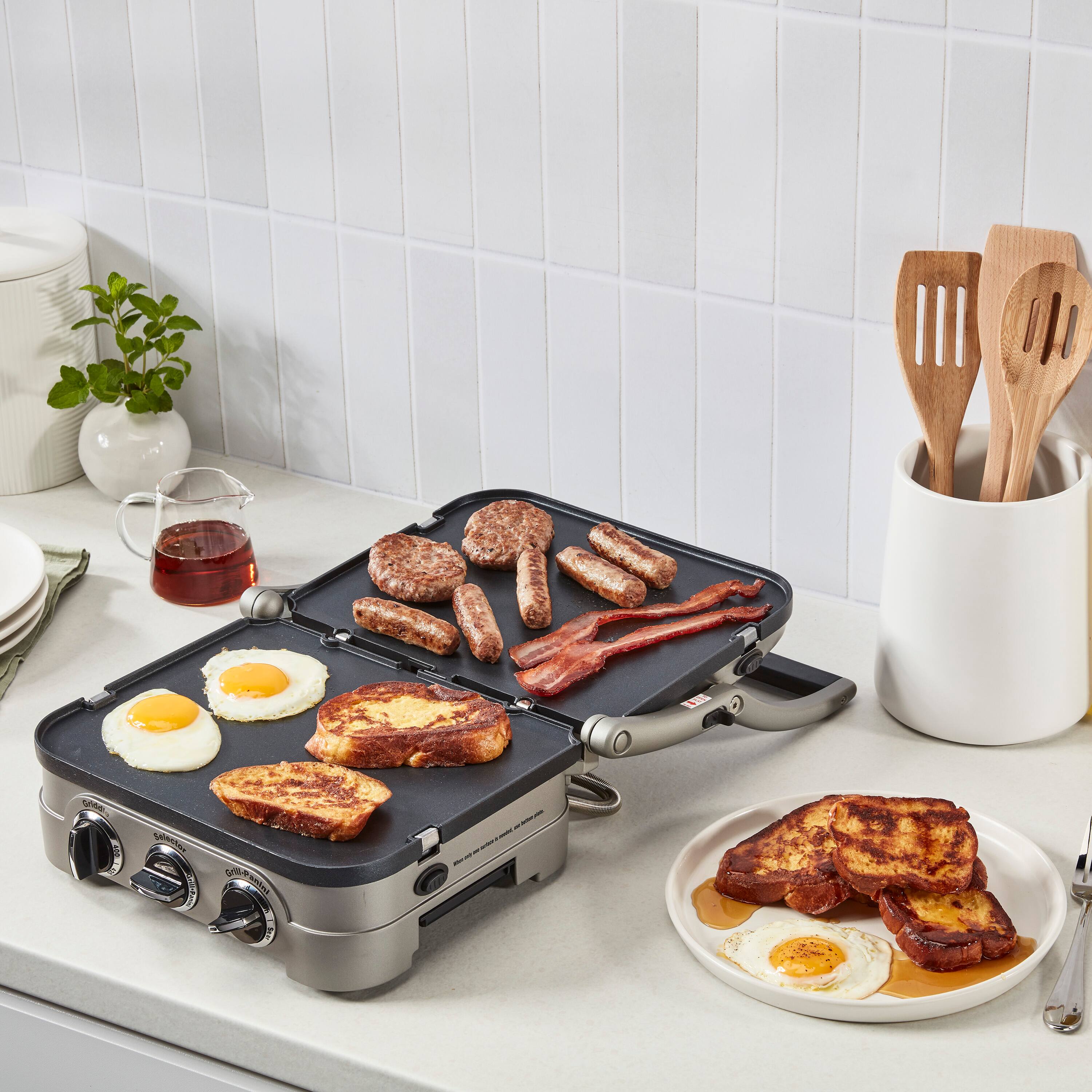 I'm sorry, but I cannot group or correct the text "L eNA anias" as it does not provide any context or information about the image. The image shows a breakfast scene with a griddle, eggs, sausage, and bacon.