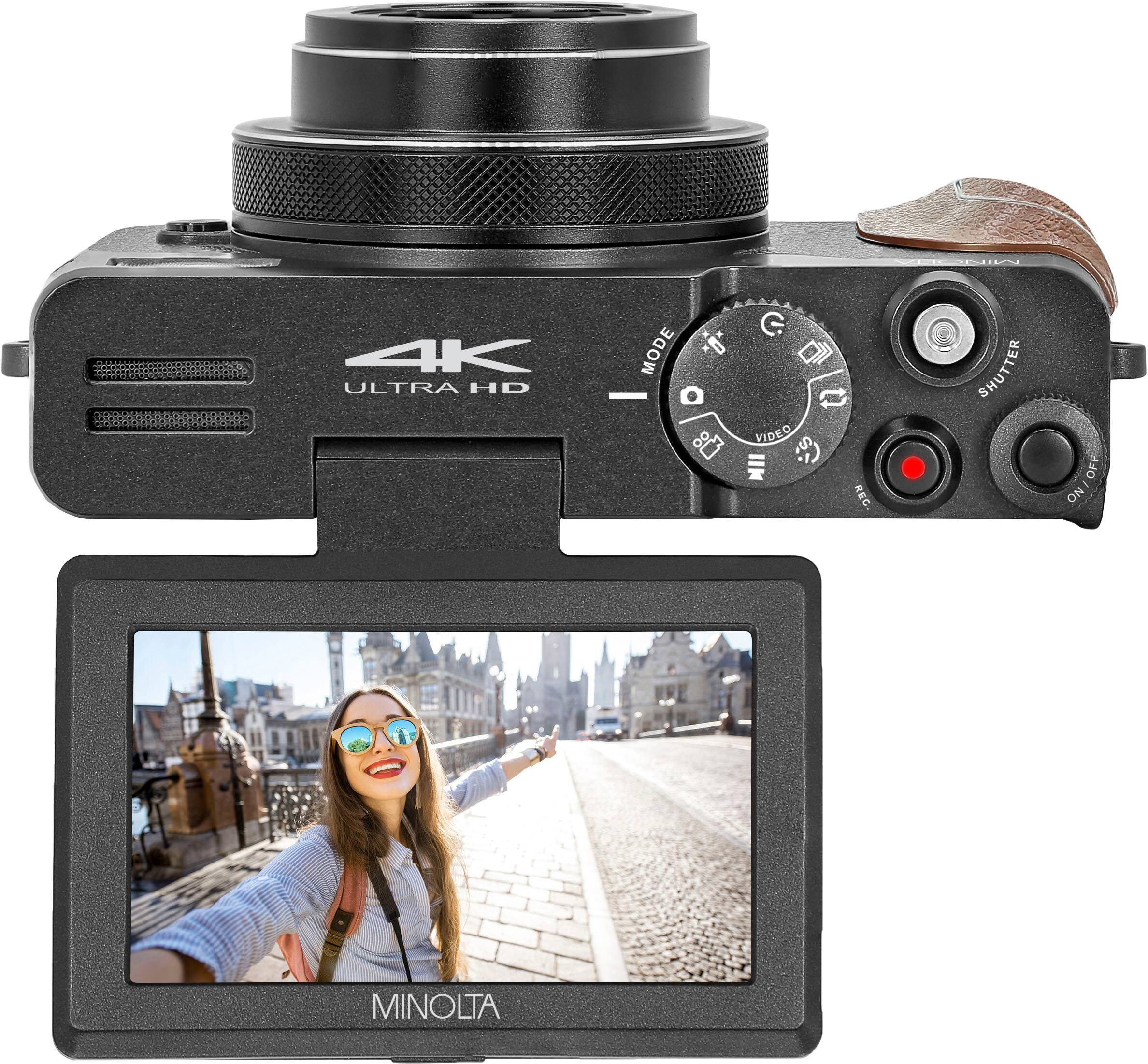 The image features a woman wearing sunglasses and a backpack, standing in front of a camera. The camera is a Minolta, and it is set to Ultra HD mode. The camera is also equipped with a viewfinder, which is currently displaying the image of the woman. The camera is positioned on a tripod, providing stability for the shot.