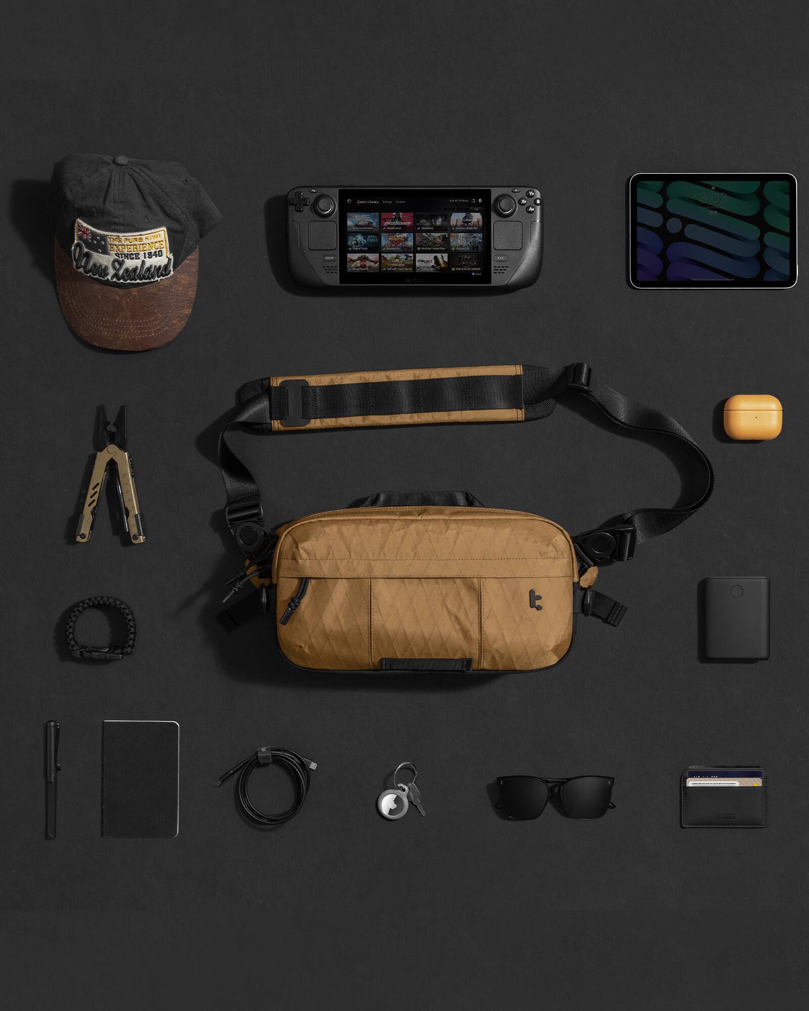 The image features a collection of items, including a brown bag, a hat, a cell phone, a camera, a wallet, and sunglasses. The items are arranged neatly on a table, with the cell phone and camera placed next to each other. The brown bag is positioned towards the top left of the table, while the hat is located near the center. The wallet and sunglasses are placed towards the right side of the table. The overall arrangement showcases a variety of personal belongings and accessories.