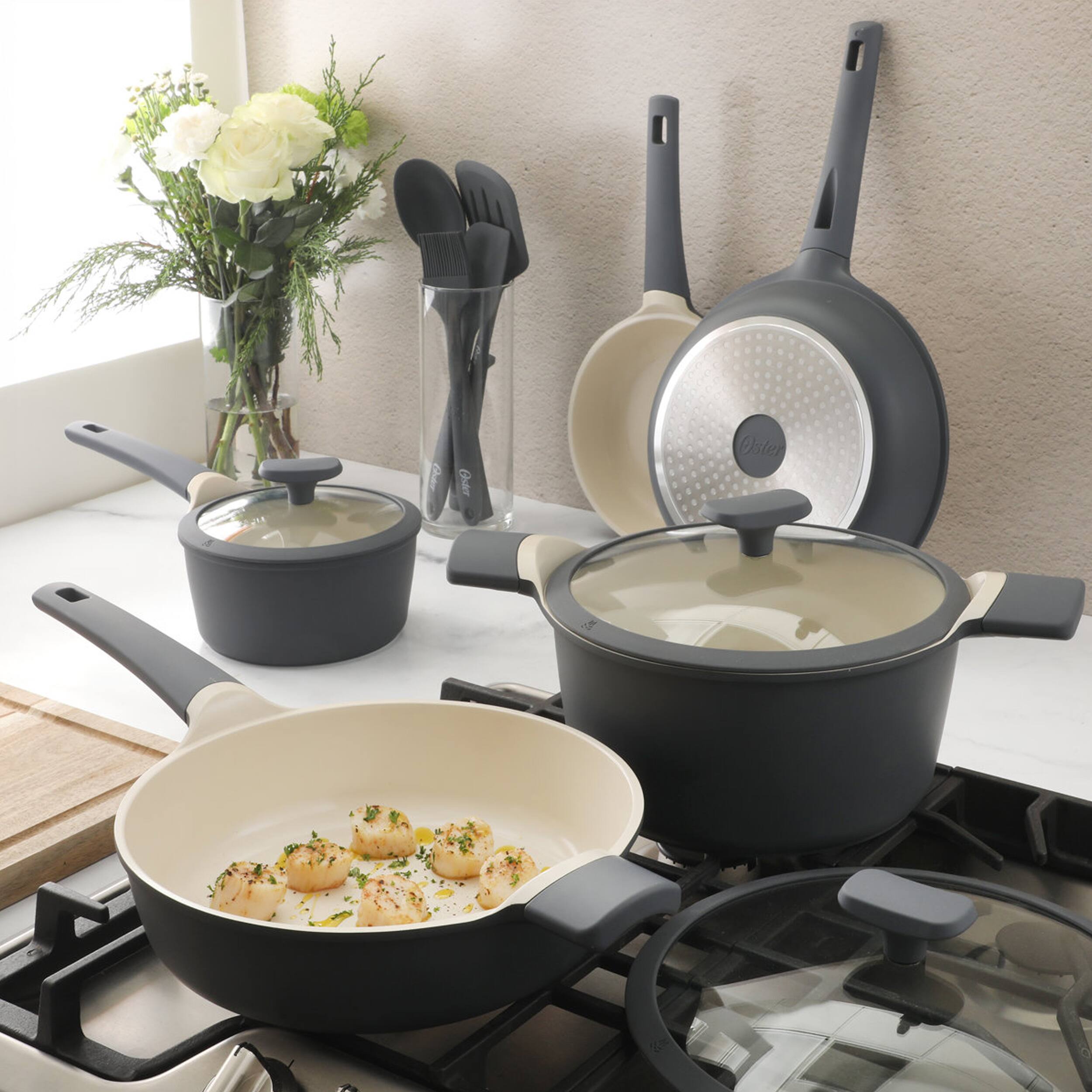 The text on the image reads:

- "Oster" (on the lid of the frying pan and the pot)
- "Oster" (on the spatula set)