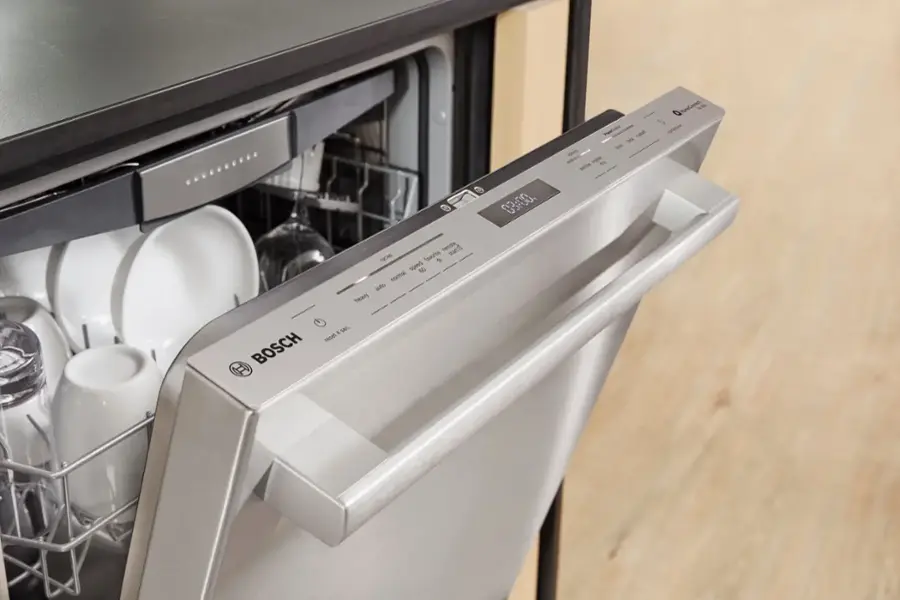The image shows a dishwasher with its door open, revealing a silver dish rack holding a variety of dishes. The dishwasher is made by Bosch and features a digital display. The dishes include cups, bowls, and bottles, all neatly arranged on the rack. The dishwasher is designed to handle different types of dishes, offering a convenient and efficient way to clean up after meals.