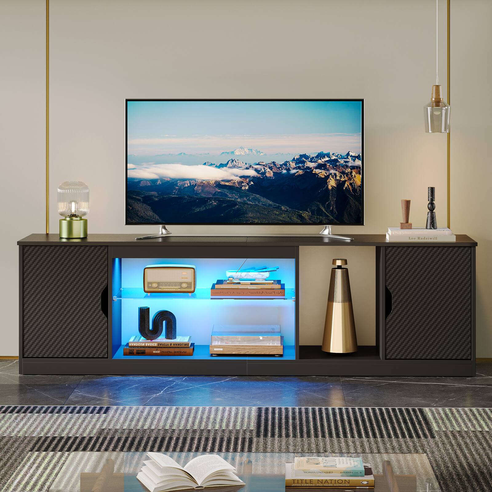 "Lea Buda" is a book that is placed on a table in front of a large flat screen TV. The TV is mounted on the wall and has a picture of mountains on the screen. The table also has a remote control and a vase on it.