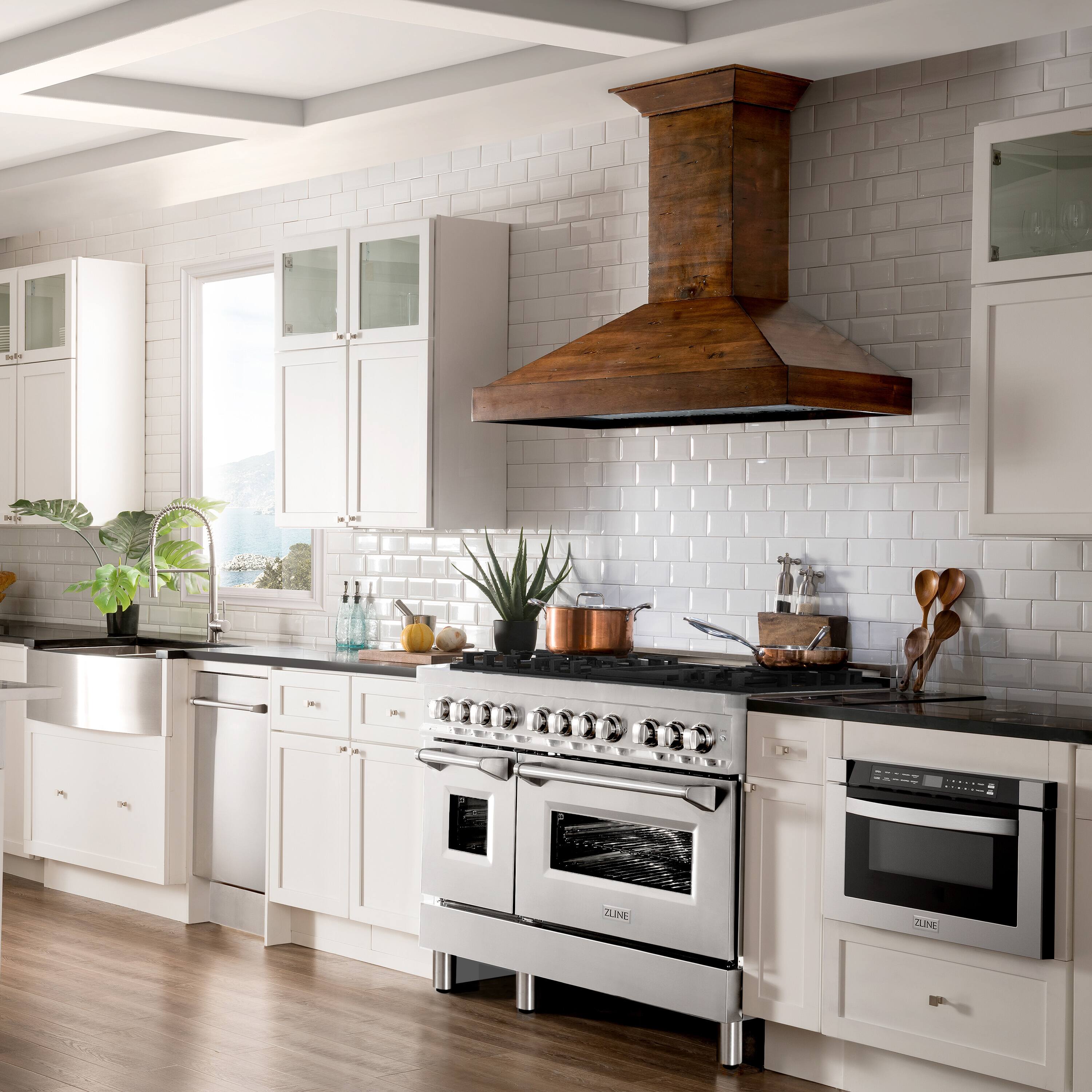 The image shows a kitchen with white cabinets and a stove top oven. The stove has a wood hood above it, and there are various cooking utensils such as spoons and knives placed on the counter. The kitchen also features a sink, a refrigerator, and a potted plant. The overall atmosphere of the kitchen is clean and well-organized, with a focus on functionality and aesthetics.