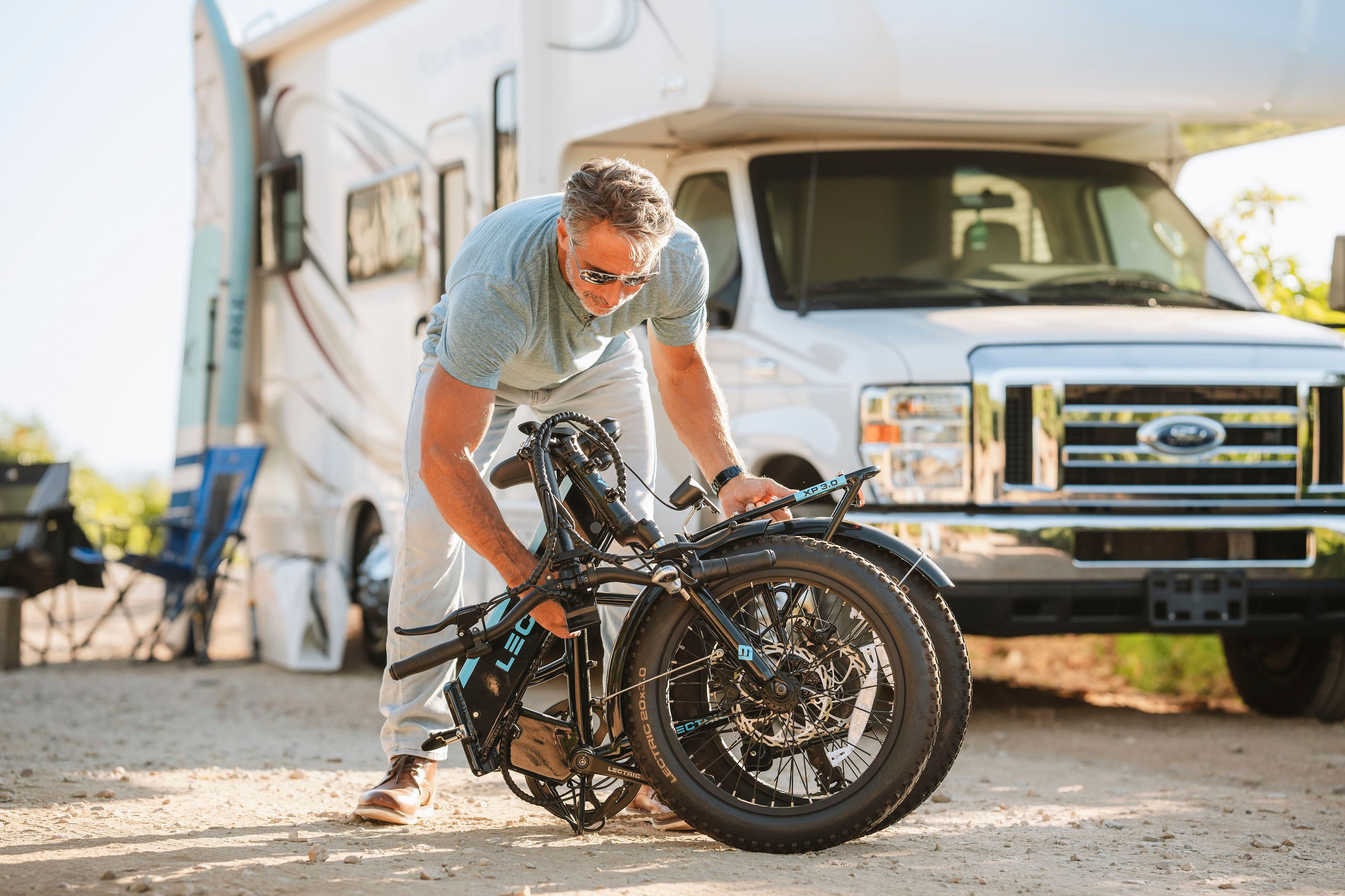 The text on the image reads "P XP30 LEC SOxSO EGT LECTRE LECTRIC 11 P V LA." However, this text does not seem to be related to the image content. The image features a man working on a motorcycle, possibly a dirt bike, in front of a truck.