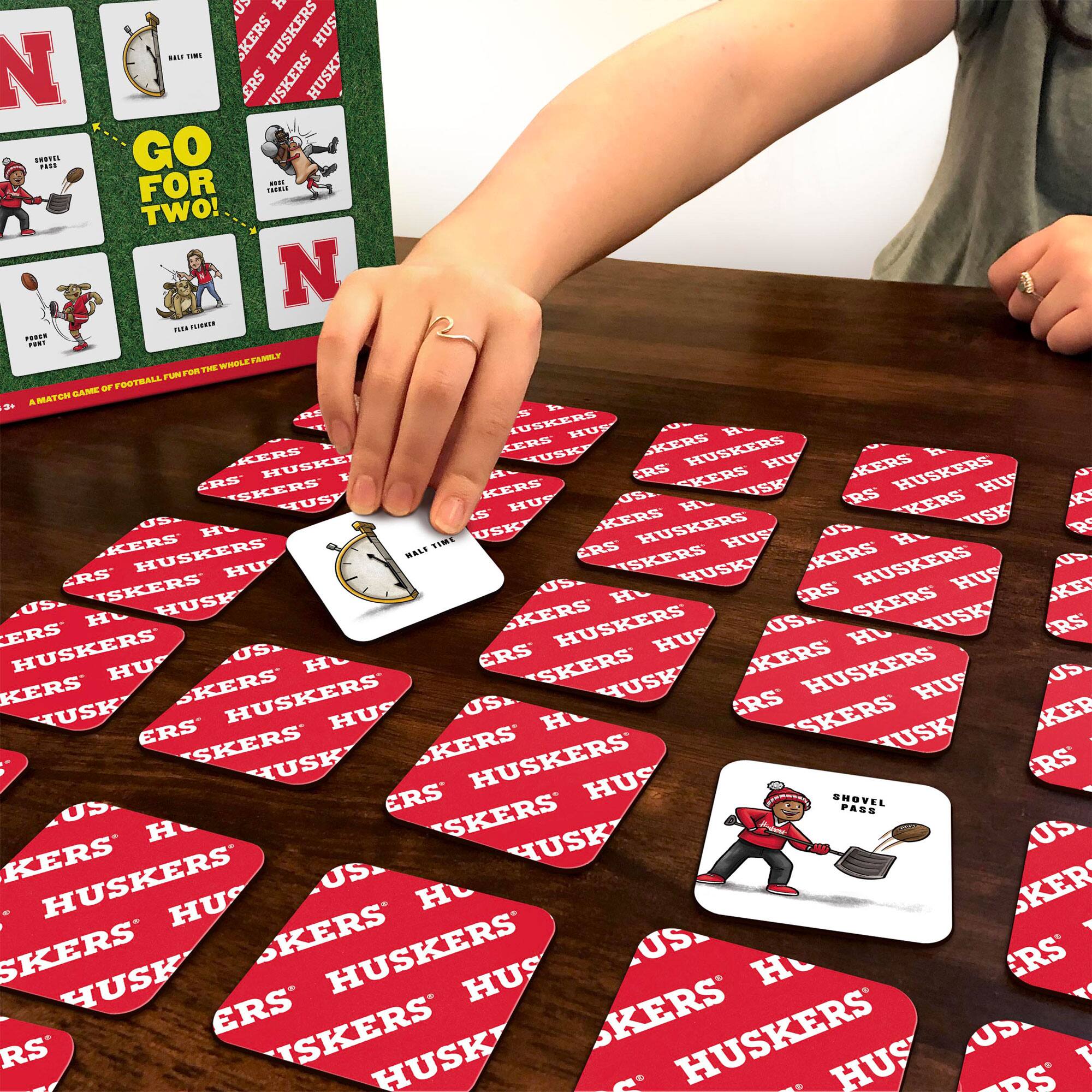 Sure, here is the corrected and grouped text from the image:

**Top Left Box:**
- GO FOR TWO!
- HALFTIME
- TRAVEL
- POUR POINT
- FLEA FUMBLE
- A MATCH GAME OF FOOTBALL FOR THE WHOLE FAMILY

**Top Right Box:**
- HUSKERS
- HUSKERS
- HUSKERS
- HUSKERS

**Bottom Left Card:**
- SHOVEL PASS

**Bottom Right Card:**
- HALFTIME

**Cards on Table:**
- HUSKERS
- HUSKERS
- HUSKERS
- HUSKERS
- HUSKERS
- HUSKERS
- HUSKERS
- HUSKERS
- HUSKERS
- HUSKERS
- HUSKERS
- HUSKERS
- HUSKERS
- HUSKERS
- HUSKERS
- HUSKERS
- HUSKERS
- HUSKERS
- HUSKERS
- HUSKERS
- HUSKERS
- HUSKERS
- HUSKERS