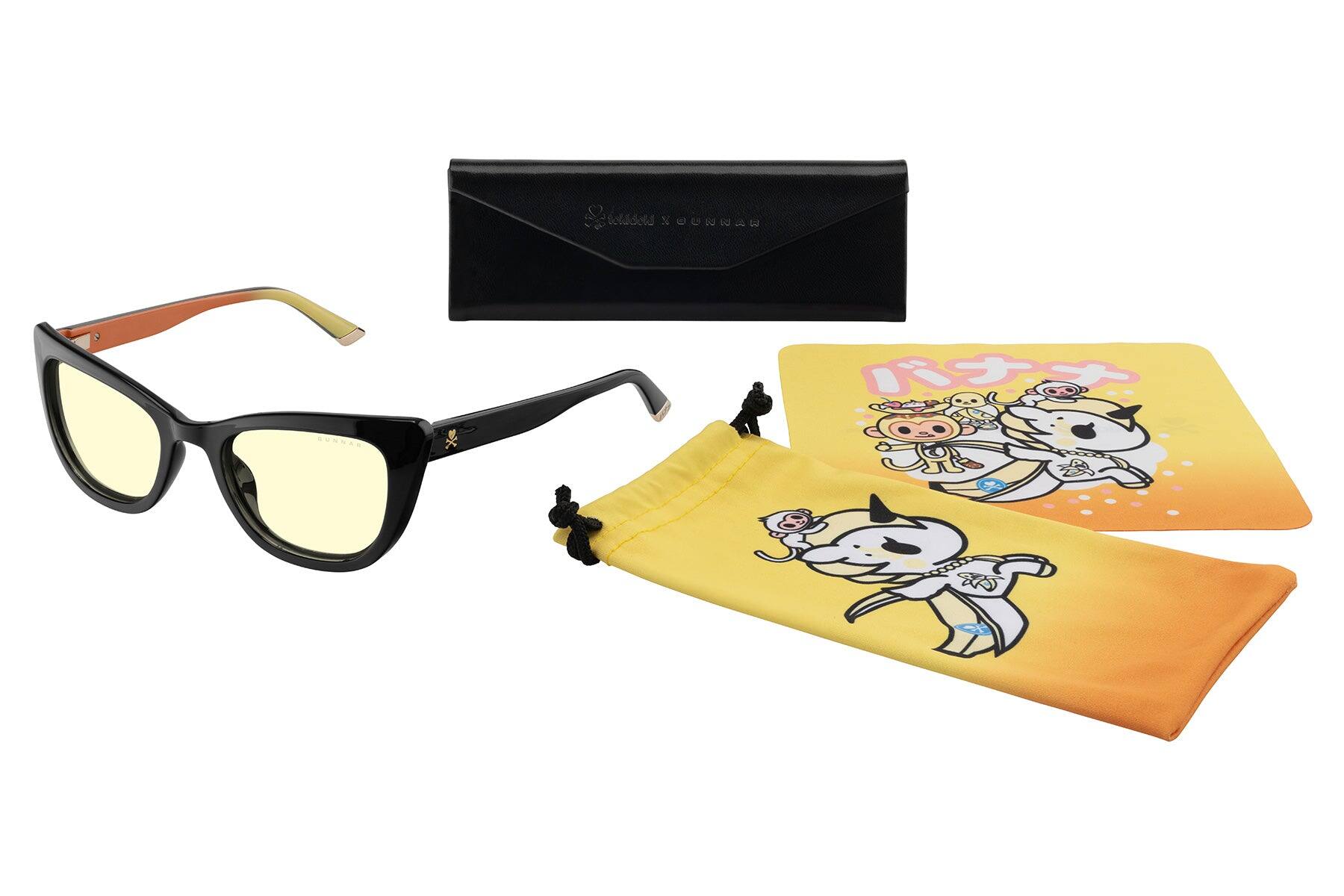 Sure, here is the corrected and grouped text from the image:

1. On the glasses:
   - "GUCCI"

2. On the black case:
   - "GUCCI YOUNG VERSACE"

3. On the yellow card:
   - "バナナマン" (Banana Man)

4. On the yellow pouch:
   - "バナナマン" (Banana Man)