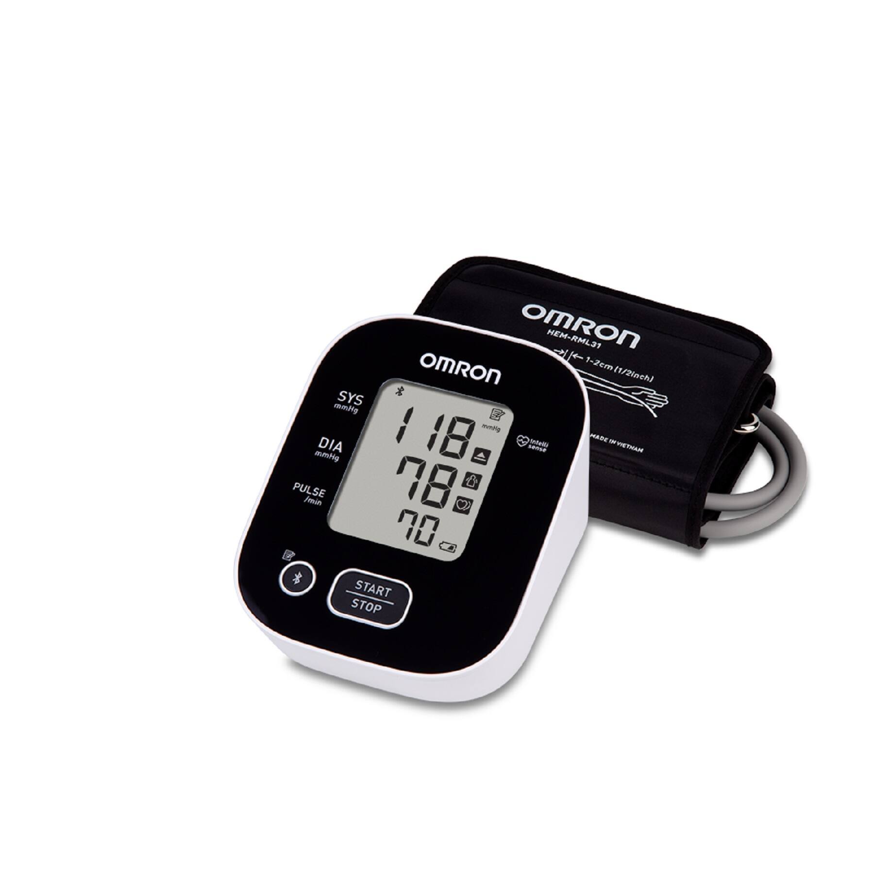 The image features a black and white Omron blood pressure monitor and a black case. The monitor has a digital display and is designed for use with a cuff. The cuff is placed around the arm, and the monitor is used to measure blood pressure. The monitor is placed on a white background, making it the main focus of the image.