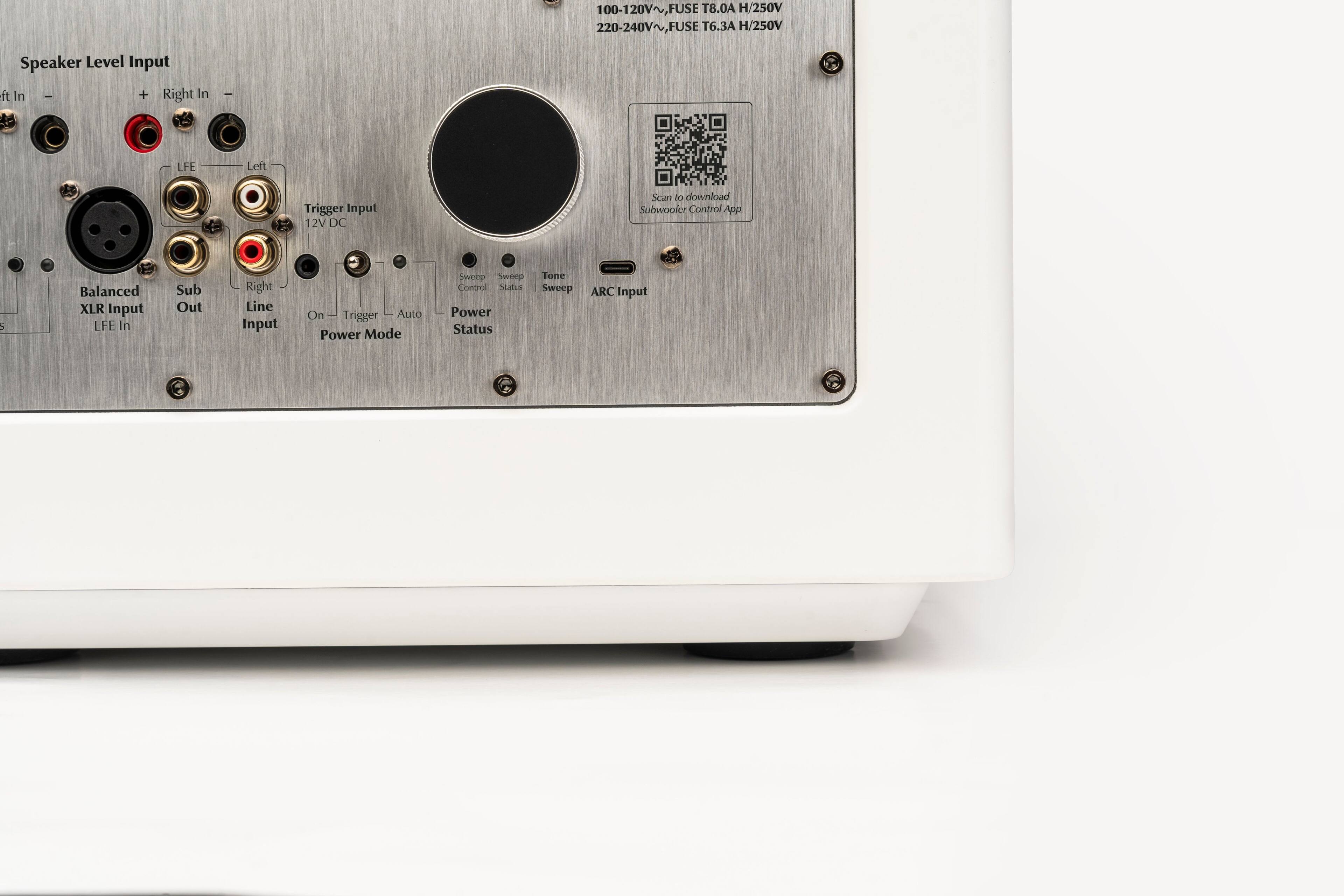 The text on the image reads: "100-120V~ FUSE T8.0A H/250V 220-240V~, FUSE T6.3 H/250V Speaker Level Input it In - + Right In I LFE Left Trigger Input 12V DC Scan to download Subwooler Control App 5 Balanced XLR Input LFE In Sub Out Right Line Input On Trigger Auto Power Mode Sweep - ARC Input."