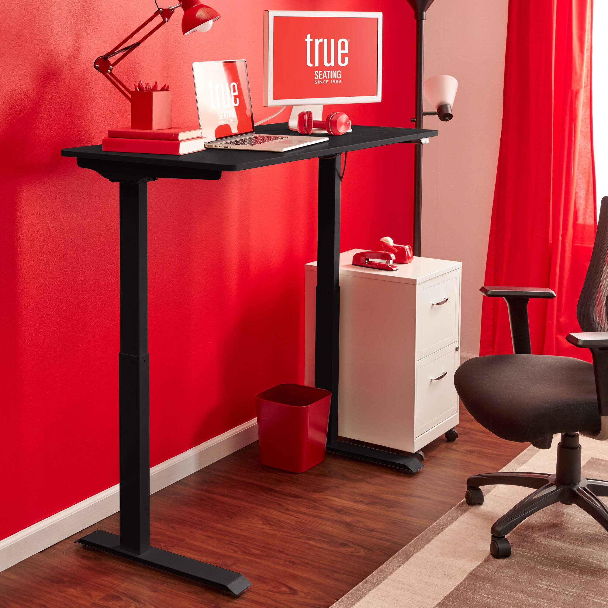The image features a red room with a desk and a chair. The desk has a laptop and a computer monitor on it, and there is a red trash can nearby. The room also has a red chair and a red desk. The room is decorated with red walls and curtains, giving it a vibrant and bold appearance. The desk is placed in front of a window, providing natural light to the workspace.