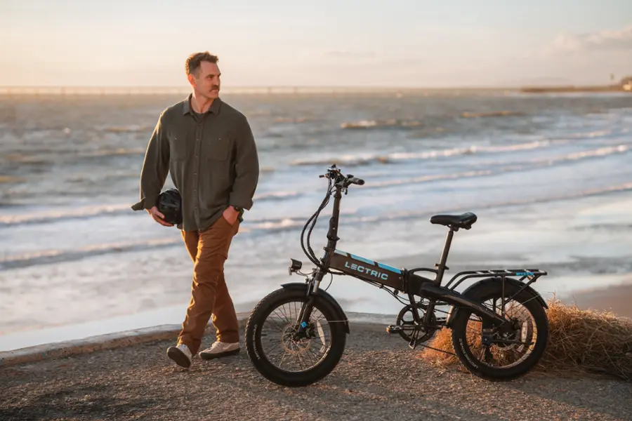 The man is standing next to a black electric bicycle.