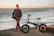The man is standing next to a black electric bicycle.