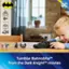 The image features a young boy playing with a toy Batmobile, which is a part of the Tumbler Batmobile set from the Dark Knight movies. The boy is sitting at a dining table, surrounded by various items such as a potted plant, a vase, and a bowl. The scene captures the excitement and fun of playing with toys, especially when they are inspired by popular movies like the Dark Knight series.