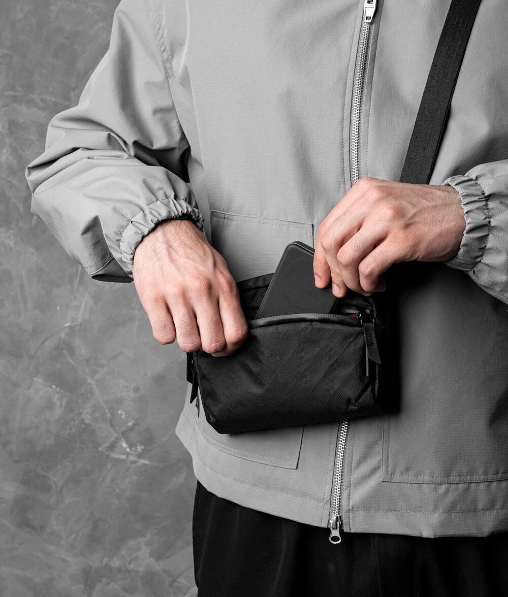 Alt View 1. ALPAKA - Flight Sling 1L Travel Sling Bag, Lightweight Crossbody Pouch, Phone Sleeve, Passport Pocket, Detachable Strap - Black Ultradyne 100D.