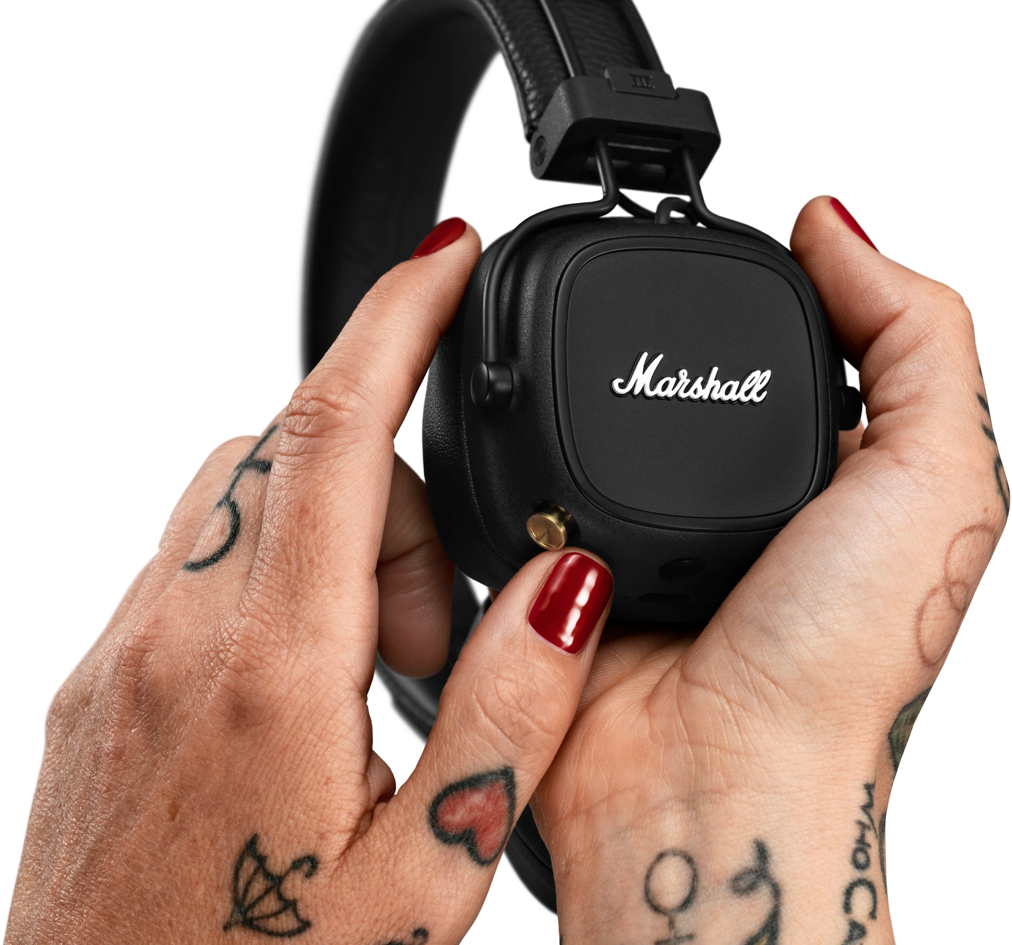 Marshall headphones are being held by a person with tattoos on their hand.