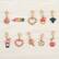 The image shows a collection of various charm earrings, including a pair of earrings that say "juicy."