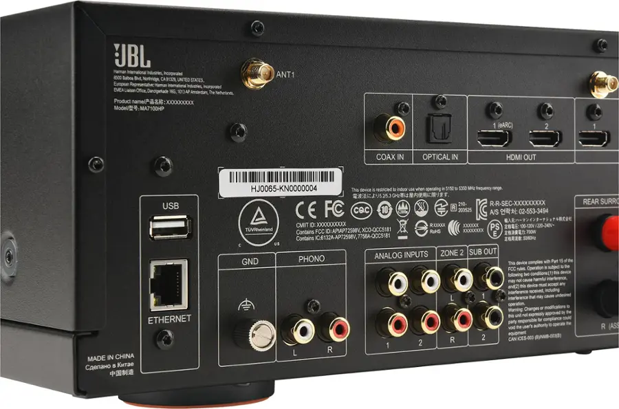 The text on the image reads:

"JBL Haman international industries incorporated 8500 Balboa Blvd, Northridge, CA 91329, UNITED STATES. European Representative Haman international Industries, incorporated EMEA Liaison Office, Danzigerade 16G 1013AP The Amsterdam, Netherlands. Product name/? : XXXXXXXXx Model/: MA7100HP ANT1 1 (BARC) 2 1 COAX IN OPTICAL IN HDMI OUT USB ETHERNET MADE IN CHINA HJ0065-KN0000004 This device S restricted to indoor use when operating in the 5150 D 5350 MH2 frequency range. 5.25.3 210- R-R-SEC-XXXXXXXXX FC CQc 10 R 203525 CE A/S : 02-553-3494 CMIT Dc XXXXXXXXXX RXXXXX XXXXXx PS TVRheinland FCC ID: APIAP72598V, XCO-QCC5181 RoHS XXXXXXXXxX Contains E 7OOW Contains IC-6132A-AP72598V, 7756A-QCC5181 5060 C US INPUTS ZONE 2 SUB OUT PHONO ANALOG GND complies with Part 15 of the FCC rules. conditions: this device may cause harmful interference to radio and television reception, and this device must accept any interference, including interference that may cause undesired operation."