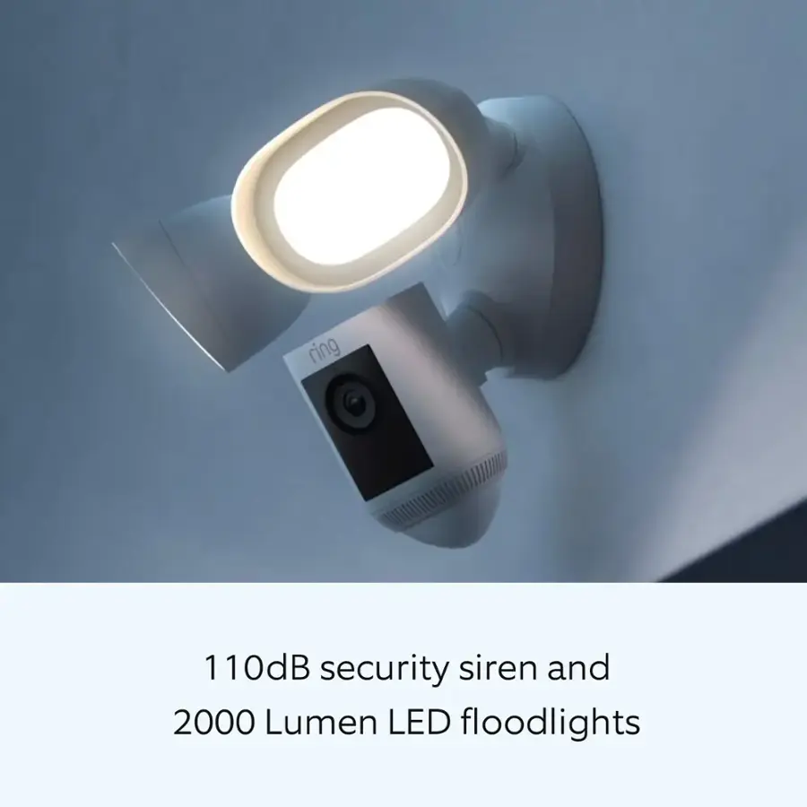 The image features a white light fixture with a security camera attached to it. The light fixture is designed to emit a 110 dB security siren and has 2000 Lumen LED floodlights to provide illumination.