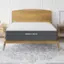 The image features a bed with a wooden headboard and a mattress. The mattress is a Ghostbed Luxe mattress, which is a high-quality and comfortable option for a good night's sleep. The bed is placed on a white carpet, and there is a nightstand next to it.