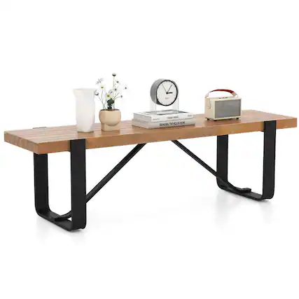 The image features a wooden bench with a clock, a vase with flowers, and a book on it. The clock is placed near the center of the bench, while the vase with flowers is positioned to the left of the clock. The book is located on the right side of the bench. The scene appears to be a cozy and inviting space, possibly in a house or a public area.