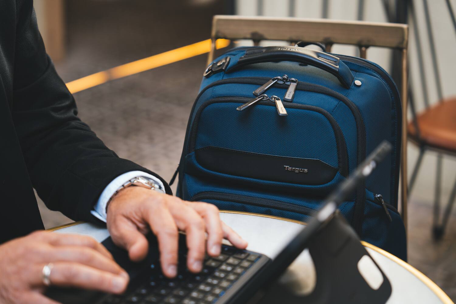 I'm sitting at a table with a laptop and a blue backpack.