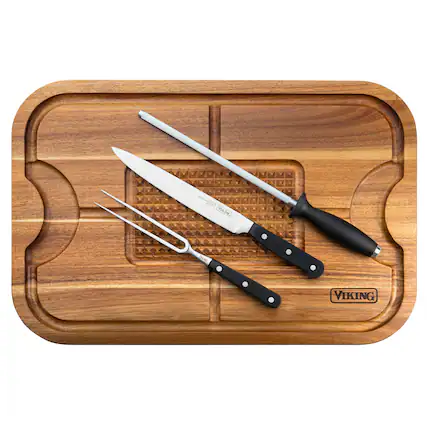 The image features a wooden cutting board with three knives and a pair of tongs on it. The knives are placed in a row, with one knife being larger than the other two. The tongs are positioned next to the knives, completing the set of kitchen utensils. The cutting board is placed on a table, ready for use in the kitchen.