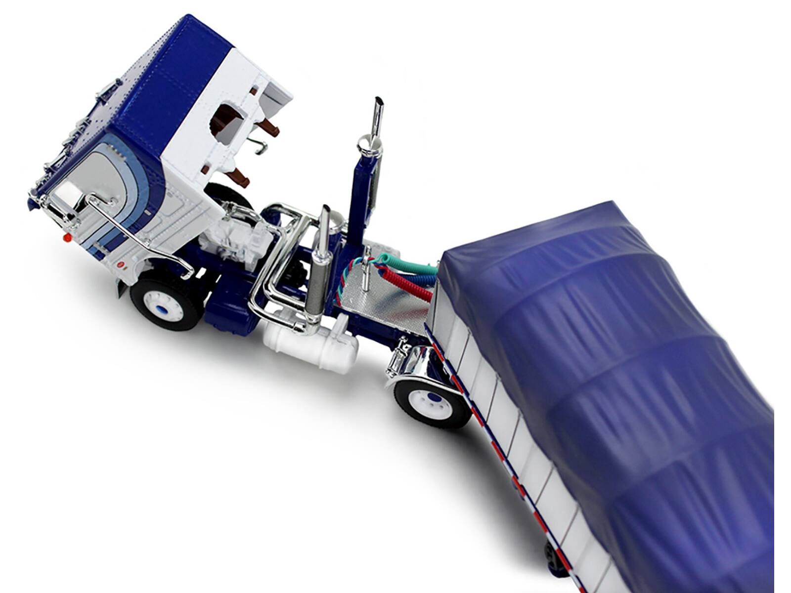 Angle. First Gear - Peterbilt 352 COE 110" Sleeper and 53’ Wilson Roadbrute Flatbed Trailer with Covered Wagon White with Blue Stripes 1/64 - White and Blue.