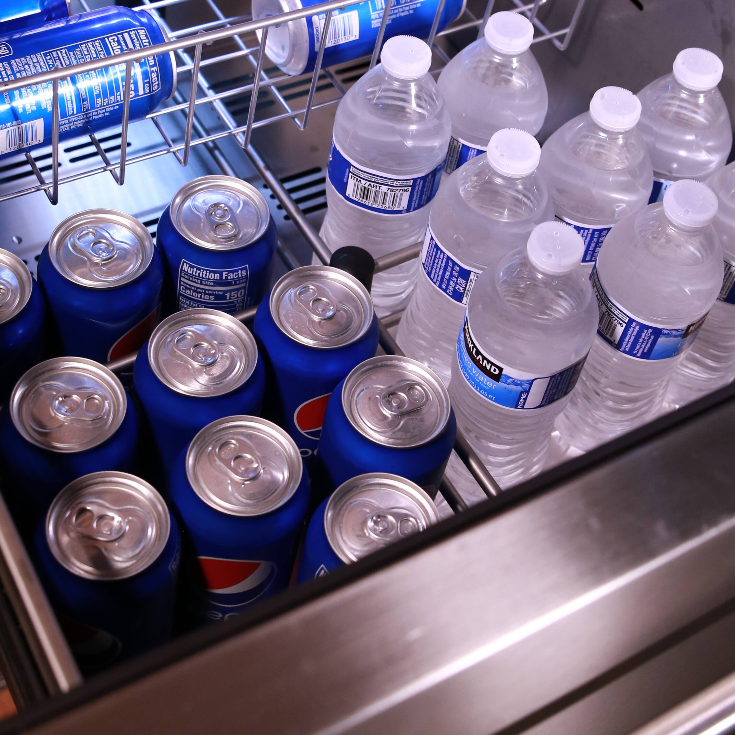 The image shows a refrigerator with a variety of drinks, including water and soda. There are several cans of soda, such as Pepsi, and a few bottles of water. The refrigerator is well-stocked with these beverages, providing options for different preferences and needs.