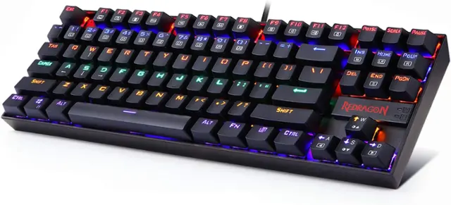 The image features a close-up of a black keyboard with colorful lights underneath it. The keyboard has a variety of keys, including letters, numbers, and function keys. The keys are arranged in rows, with some keys having multiple functions. The keyboard is designed by Redragon and is likely intended for gaming or other computer-related activities.