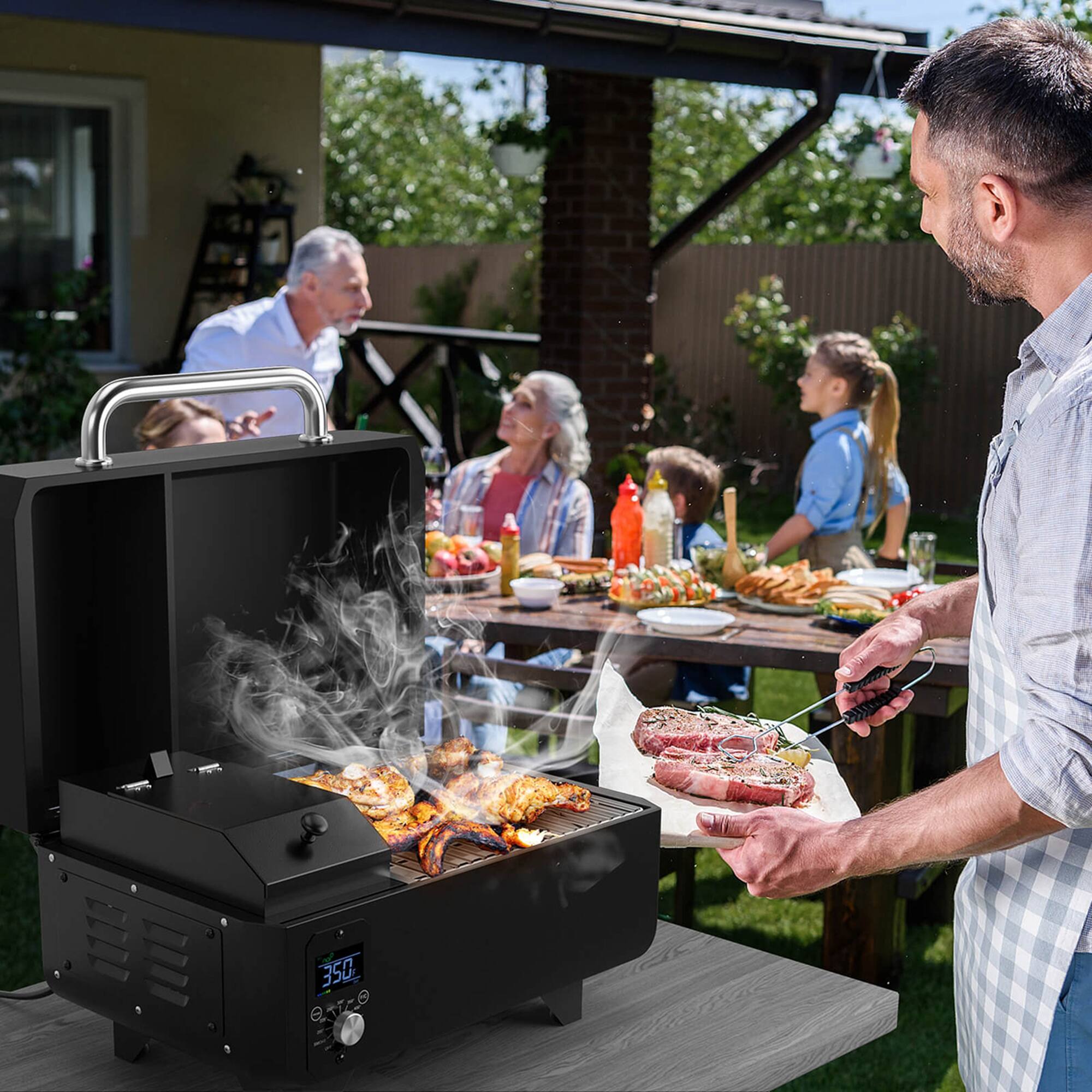 The man is standing next to a grill, which is labeled "PATC 350." He is holding a plate of food and appears to be serving himself or others. The scene also includes a dining table with various items such as cups, bowls, and bottles. There are other people in the background, suggesting a social gathering or a family meal.